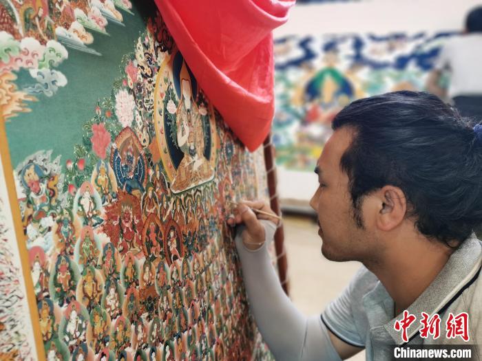 圖為更登才讓的徒弟繪畫唐卡?！?zhí)砀?攝